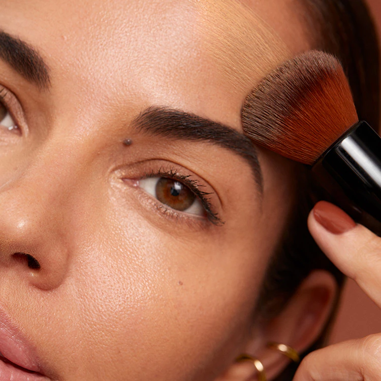 Close up of model eye showcasing defined brows and a natural, shimmery eye look