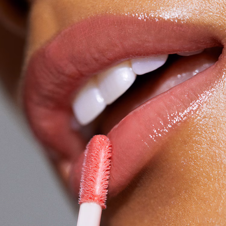 Close up of model applying Crushed-Oil Infused Gloss to lips