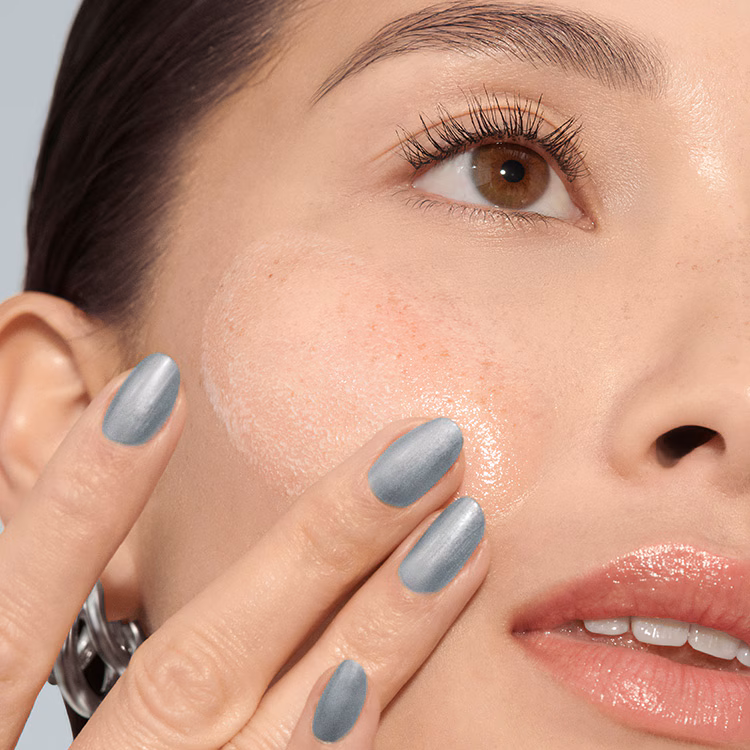 Model applying Skin Long-Wear Weightless Foundation to skin with a foundation brush